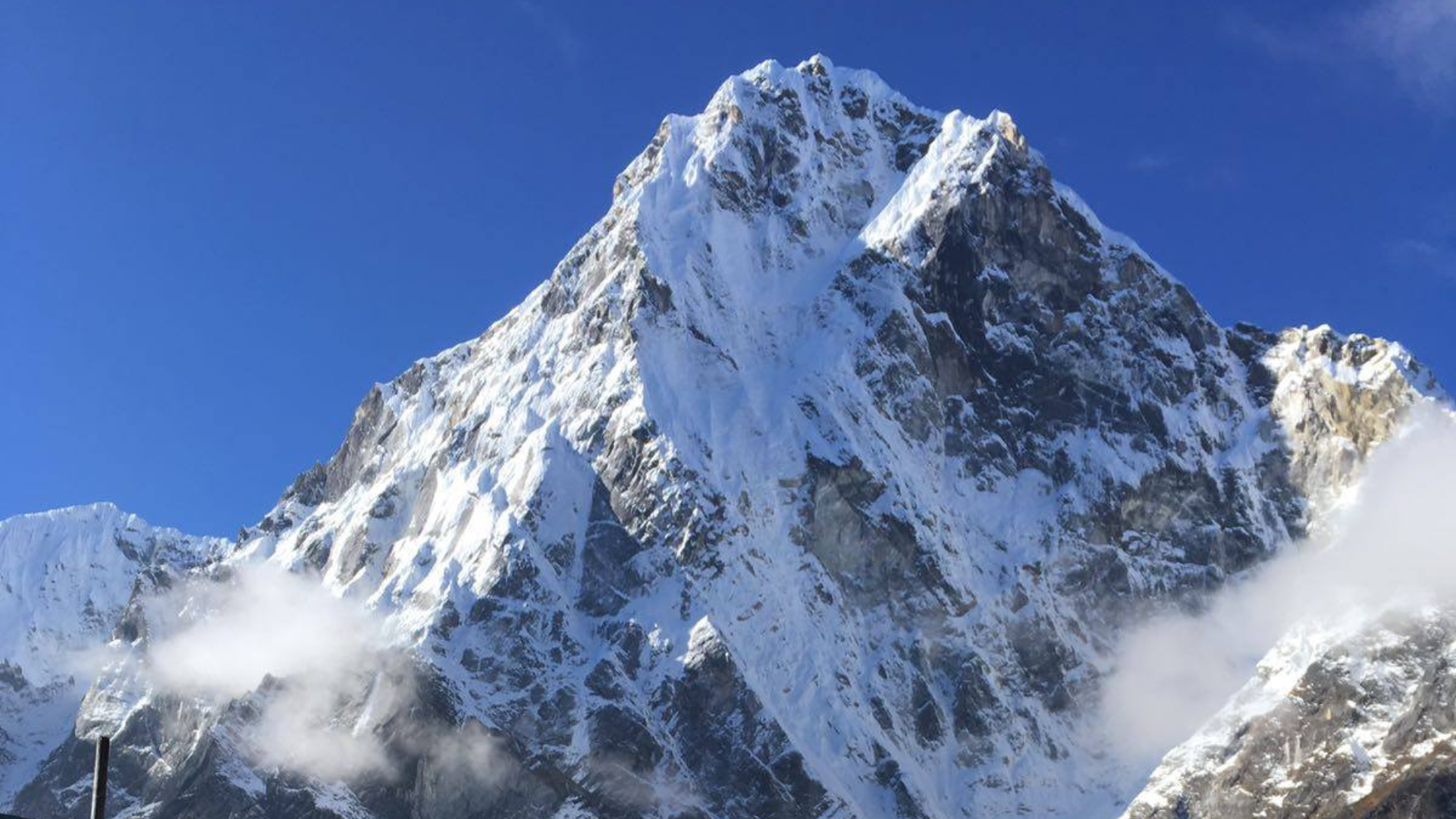 Climbers ascending Everest Island Peak with snow ridges and towering Himalayan peaks under a clear blue sky.