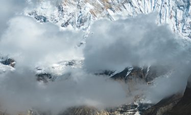 Stunning view of snow-capped Annapurna peaks with dramatic clouds in Nepal's Himalayas.