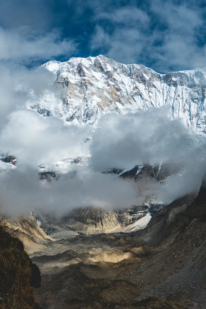 Stunning view of snow-capped Annapurna peaks with dramatic clouds in Nepal's Himalayas.