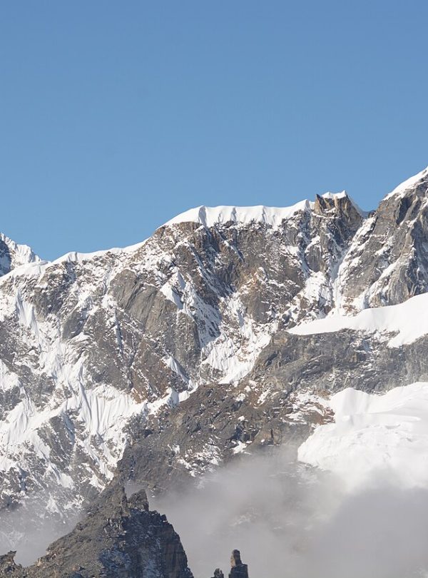 Climber on Lobuche Peak with panoramic views of Everest and Himalayan mountains.