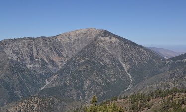 Climber ascending Baden Powell Peak with Langtang Valley and snow-capped mountains in the background