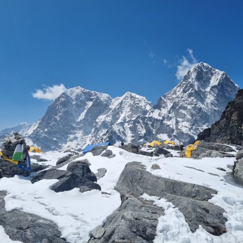 Snow-covered Himalayan peaks and colorful prayer flags at a base camp in Khumjung, Nepal.