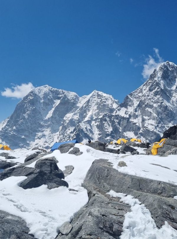 Snow-covered Himalayan peaks and colorful prayer flags at a base camp in Khumjung, Nepal.