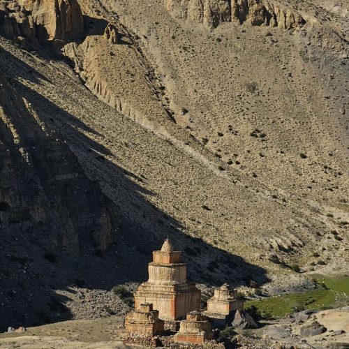 Remote ancient stupa in Mustang, Nepal, nestled in barren, rocky terrain under the bright sun.