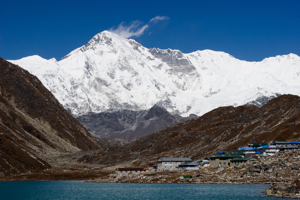 Stunning view of snow-covered Mount Cho Oyu towering over Gokyo Ri in Nepal, with a serene lake in the foreground.