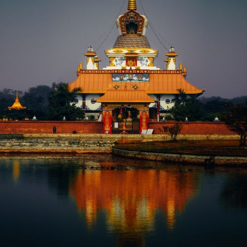 Captivating view of a Buddhist temple reflecting on a serene pond at dusk in Lumbini, Nepal.