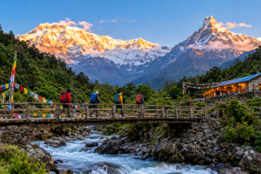 After the Rains, Annapurna Welcomes Trekkers Back 2026 Annapurna Welcomes Trekkers Back 2026crossing a wooden bridge toward Annapurna Base Camp at sunrise after the monsoon, with snow peaks glowing behind